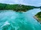 High-angle closeup of Niagara Whirlpool with ropeway lines flowing water, green trees on both sides