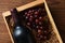 A high angle closeup of a red wine bottle in a wood crate with grapes