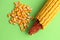 High angle closeup shot of a pile of peeled yellow corns on a green background