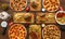 High angle closeup shot of pizzas and burgers on a wooden table