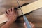 High angle closeup of a woodworker using a miter box and hand saw to cut a board