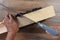 High angle closeup of a woodworker using a miter box and hand saw to cut a board at an angle