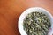 High angle closuep shot of pumpkin seeds in a white bowl on a wooden surface