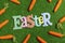High angle of Easter letters and random carrots on green grass