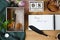 High angle of feather shape pen and notebook with text placed on wooden table with cookies, box with brushes and watch