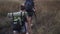 High angle footage of two travelers - man and woman are climbing the hills with tourists backpacks on the back. Morning