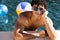 High angle portrait of biracial shirtless young man in sunglasses leaning at poolside