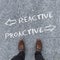 High angle shot of arrows and the words Reactive, Proactive written  in front of a man\'s shoes