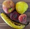 High angle shot of a banana, apples, and Saturn peaches on a wooden surface