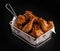 High angle shot of a basket of delicious fried chicken with hot sauce on a black surface