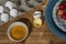 High angle shot of beaten eggs in a small bowl with and strawberries on a plate on the wooden table