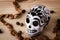 High angle shot of black and white Calavera skull statue with coffee beans on a wooden table