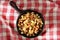 High angle shot of a cast iron skillet with country style hash brown potatoes on a red checked table cloth with warm side light