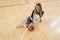 High-angle shot of a cheerleader sitting on the floor with her hand on a basketball and her eyes closed. Sport concept.