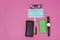 High angle shot of a face mask, glasses, watch, cellphone, wallet and sanitizer on a pink surface