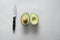 High angle shot of a fresh delicious avocado with a knife on a white surface