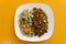 High angle shot of fried rice, Chinese noodles with chicken veggies isolated on a yellow background