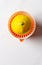 High angle shot of a half lemon and hand juicer on a white marble kitchen surface