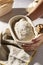 High angle shot of hands holding banneton basket with sourdough