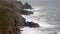 High-angle shot of high tide waves swashing some cliffs in Cornwall, South West England