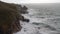 High-angle shot of high tide waves swashing some cliffs in Cornwall, South West England