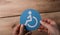 High angle shot of a man holding a blue and white wheelchair symbol