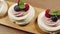 High angle shot of mini Pavlova cakes with strawberry whipped cream filling decorated with fresh berries and mint leaves