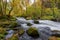 High angle shot of mossy stones in the foamy river flowing in the forest