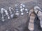 High angle shot of a pair of flip flops and some rocks shaped like the word Ana on the sand