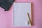 High angle shot of a pencil and an eraser on a journal on a pink surface