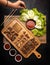 High angle shot of a person grabbing lettuce by a plate of fried meat and potatoes