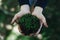 High angle shot of a person holding handfuls of mud and green grass above the ground