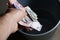 High angle shot of a person holding some cash over a garbage can