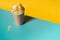 High angle shot of plain potato chips in a beige paper cup with crumbs on colorful background