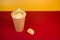 High angle shot of plain potato chips in a beige paper cup with crumbs on a yellow red background