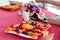 High angle shot of a plate of fruits with sophisticated decoration on a table with flowers