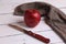 High angle shot of a red apple, a knife, and a checkered cloth on a white wooden surface