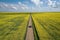 High angle shot of a road with a car in the middle of a field during daytime