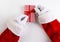 High angle shot of Santa Claus hands tying a ribbon and bow on a res and white striped Christmas Present