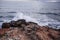 High angle shot of the seawater splashing on the mossy rocks