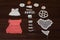 High angle shot of small crochet dresses for dolls, hearts, flowers, etc. on a dark wood surface