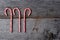 High angle shot of three holiday candy canes on a rustic wood ta