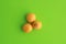 High angle shot of three small sour mangos isolated on a green surface