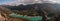 High angle shot of a turquoise reservoir surrounded by hills and greenery