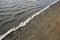 High angle shot of where the wave of the sea meets the sand