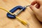 High angle shot of a yellow cable in a blue vise on a wooden surface