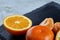 High angle still life view of sliced ruby orange and tangerine arranged together on stony board