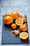 High angle still life view of sliced ruby orange and tangerine arranged together on stony board