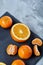 High angle still life view of sliced ruby orange and tangerine arranged together on stony board