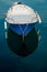 High-angle vertical shot of a moored blue fishing boat reflecting in the water